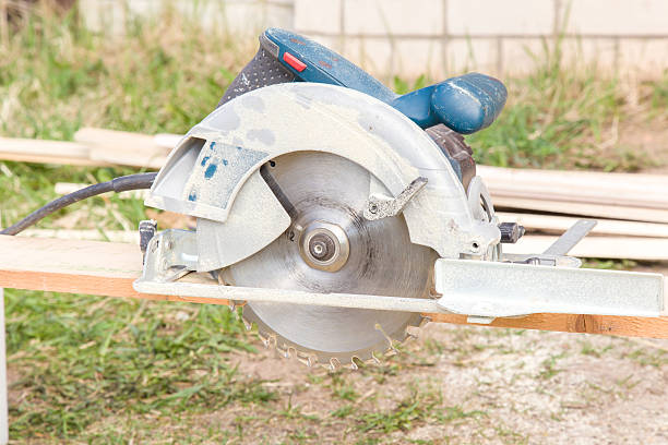 istock Carpenter using electrical powered circular saw to cut wooden plate. 591993752