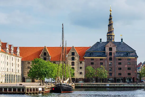 Church of Our Saviour spiel, scandinavian houses and sail ship on Christianshavn canal. Copenhagen, Denmark