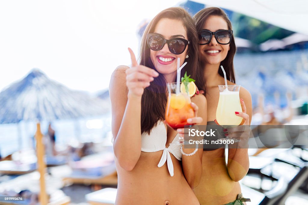 Girls drinking cocktails on beach Girls drinking cocktails on beach in bikinis Beach Stock Photo