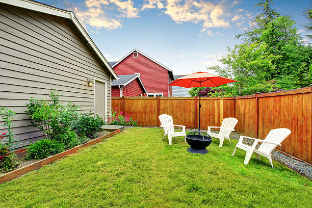 istock Fenced backyard patio with opened red umbrella , well kept lawn 591998104