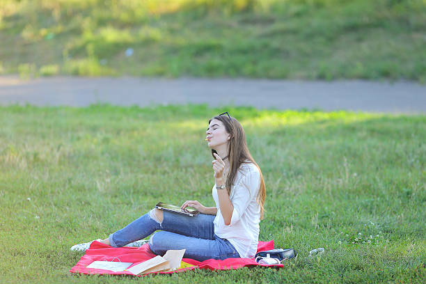 istock young girl sitting on the grass in park works at 592000384