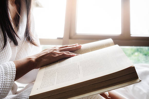 istock Reading a book.Beautiful female sitting on the bed 592000968