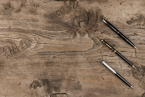 istock Black, gold and silver pens on a wooden texture 592002426