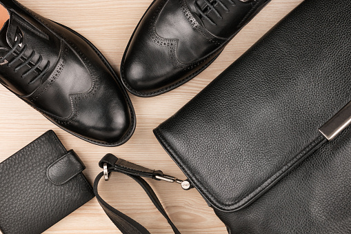 Classic black shoes, briefcase and purse on the wooden floor, can be used as background