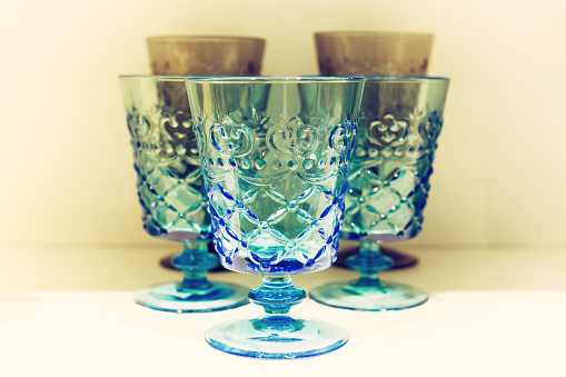 Classic blue drinking glasses on white cabinet with faded and vintage tone.