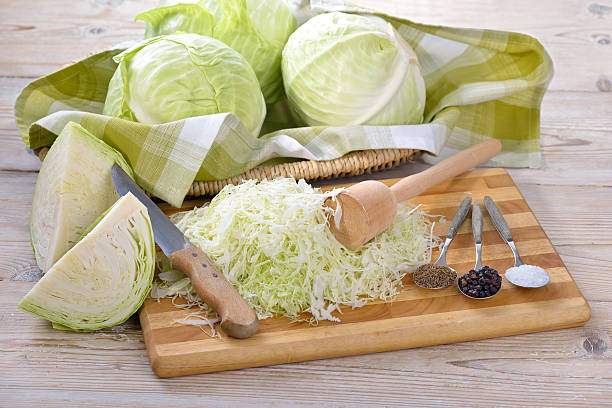 Making sauerkraut Food fermentation: Preparation for making sauerkraut: Sliced white cabbage, caraway seeds, juniper berries,  salt and a pounder   white cabbage stock pictures, royalty-free photos & images