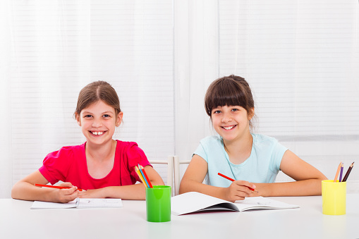 Cute little girls are enjoy drawing and writing together.
