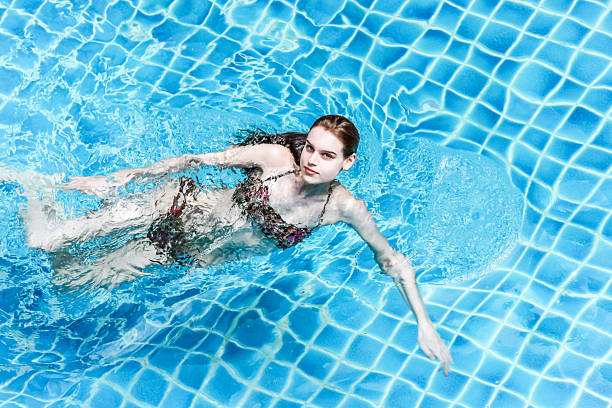 istock white girl swimming in blue pool 592007654