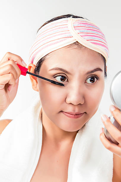 istock Asian woman applying mascara makeup on eyes by brush 592008026