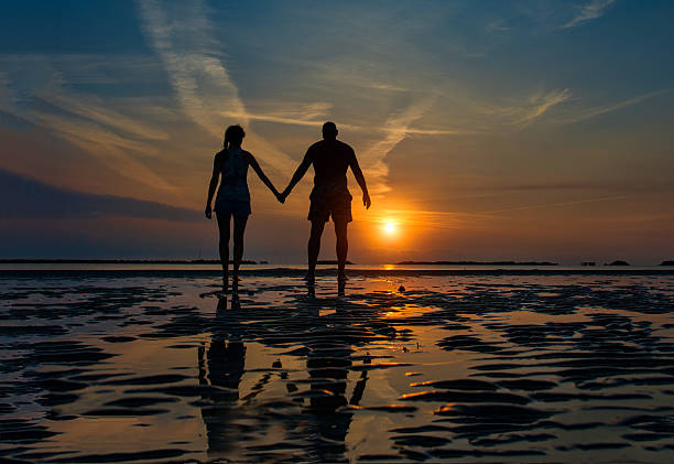 istock Couple hand in hand towards the sea 592009138
