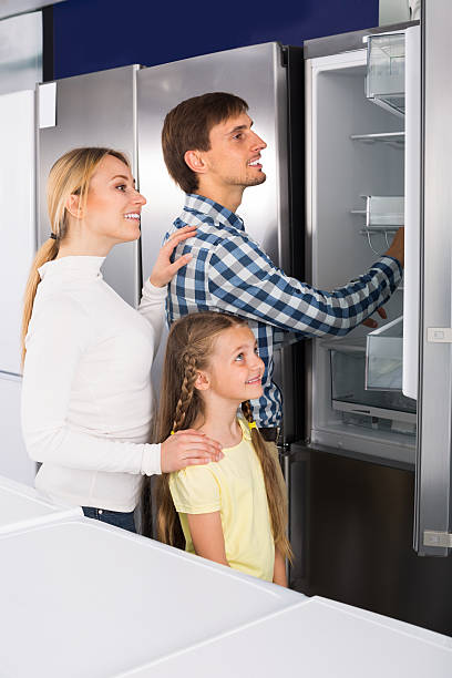 uśmiechnięta para z dziewczyną wybierającą lodówkę - three different refrigerators zdjęcia i obrazy z banku zdjęć