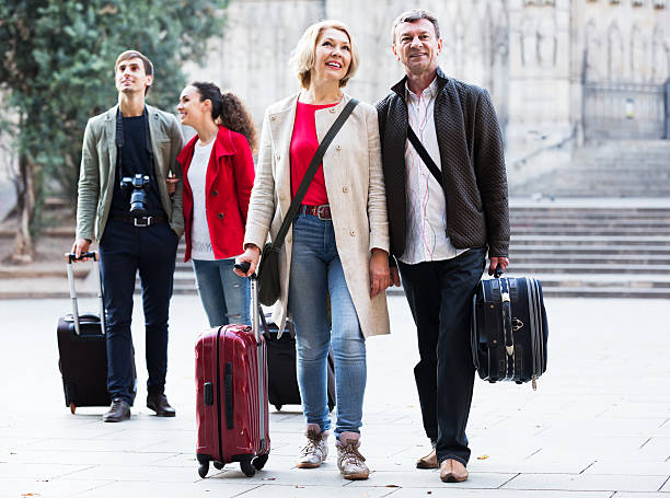Group of tourists in casual with luggage stroll along the streets outdoors
