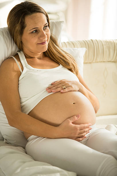 istock Pregnant woman lying down in bed, smiling 592014736