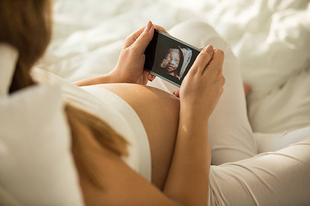 femme enceinte regardant la photo échographique 3d de son bébé - using computer bedroom one woman only cheerful photos et images de collection