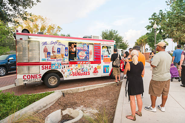 Female Small Business Owner Sells Ice Cream From Truck Kissimmee Kissimmee, United States - August 20, 2016: On a Saturday afternoon at the Kissimmee Lakefront park a woman runs a small business from a parked ice cream truck. People look to see what sweets she is selling. ice cream van stock pictures, royalty-free photos & images