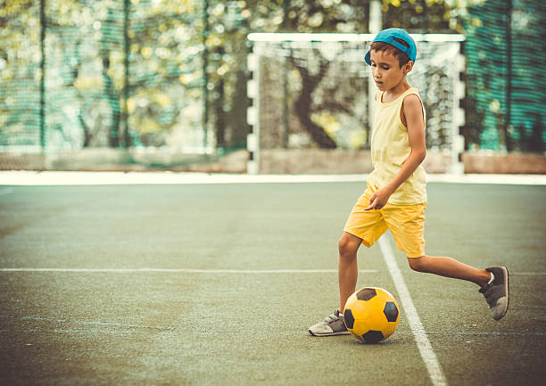istock Boy with  football ball on stadium 592025836