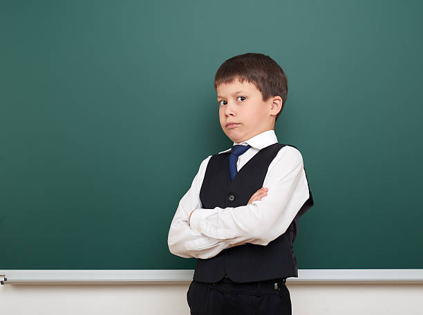 istock school student boy posing at the clean blackboard, education concept 592025940