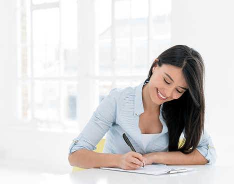 Casual Latin American woman signing documents or studying and looking very happy