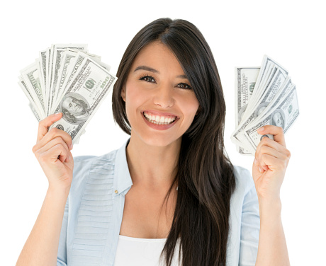 Portrait of a very happy woman holding cash in her hands and looking at the camera smiling - isolated over white background