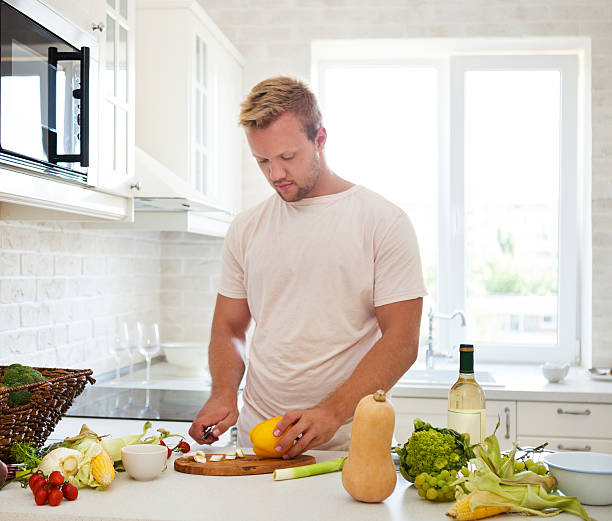 istock Handsome man cooking at home preparing salad in kitchen 592030170