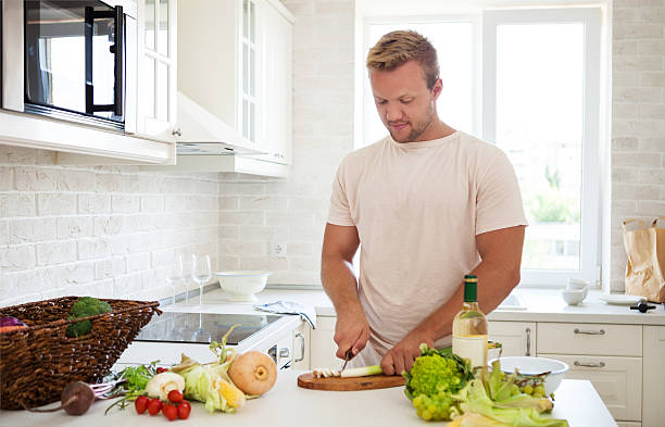 istock Handsome man cooking at home preparing salad in kitchen 592030254