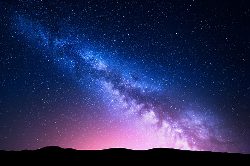 Vía Láctea y luz rosa en las montañas. Paisaje colorido de la noche. photo