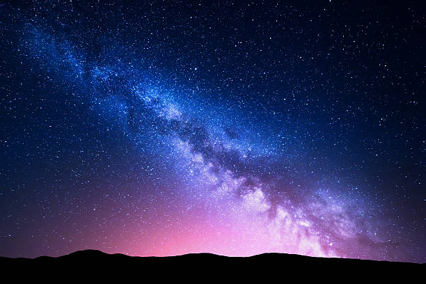 via lattea e luce rosa in montagna. paesaggio colorato notturno. - spazio cosmico immagine foto e immagini stock