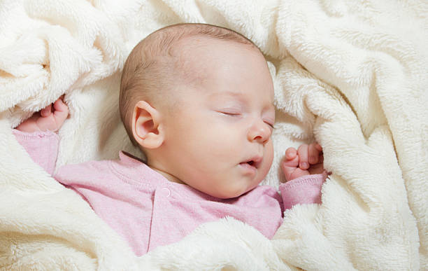 istock Newborn baby sleeping on its back on soft blanket. 592035418