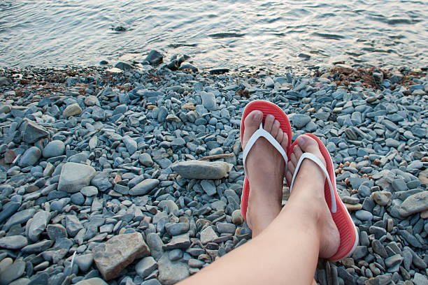 Flip-flops with sea stones on the beach. Sea background.