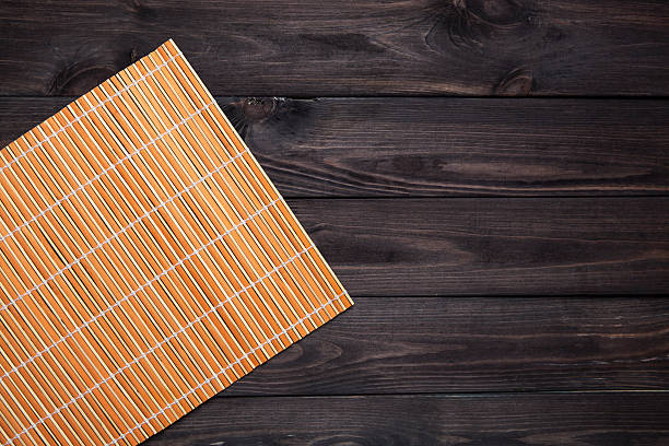 Bamboo mat on wooden table, top view orange bamboo napkin on a dark wooden table, top view bamboo material photos stock pictures, royalty-free photos & images