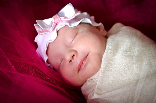 спящая новорожденная девочка в слинге на голове - child outdoors bow horizontal стоковые фото и изображения