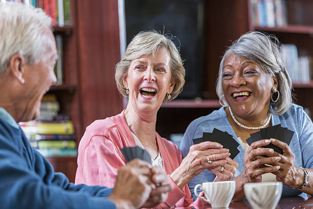 istock Multiracial group of seniors talking, playing card game 592362752