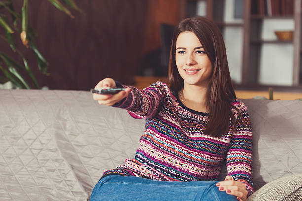 istock Young woman relaxing at home, watching television 592363890