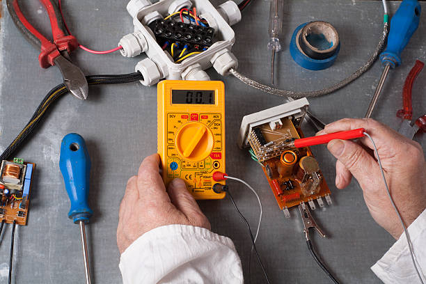 istock Hand of electrician with multimeter probe at  electrical switchgear cabinet 592370444