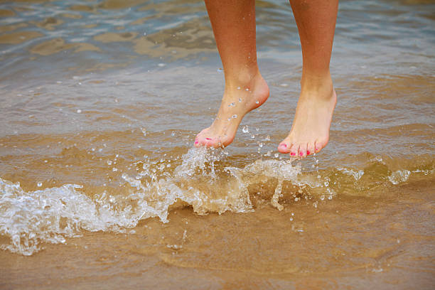 istock Female feet jump on beach. 592372080