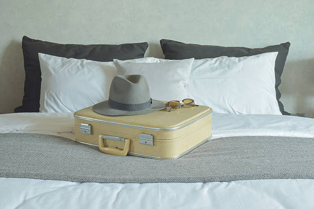 istock Hat, sunglasses and vintage travel bag setting on bed 592374106