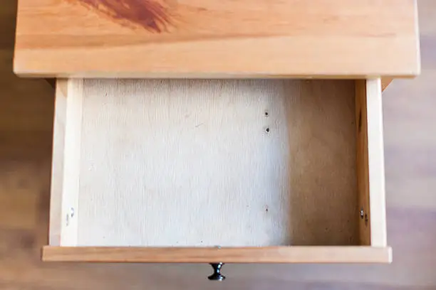 Photo of empty open drawer of wooden nightstand