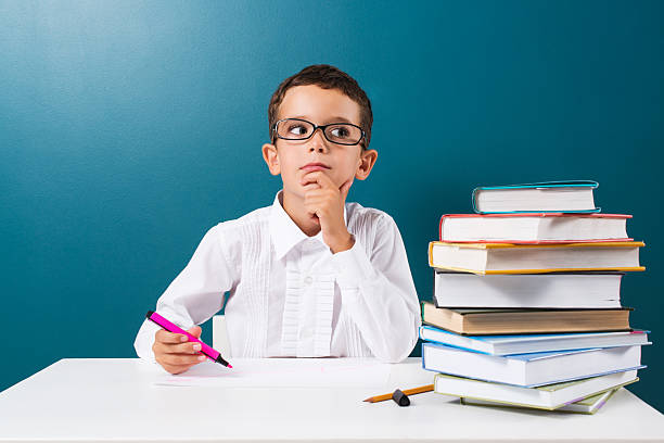 istock Cute little boy with books on the table 592383692