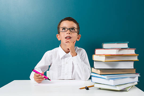 istock Contemplative cute little boy with books on the table 592383712