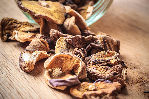 istock Dry mushrooms in jar on wooden table. 592387794