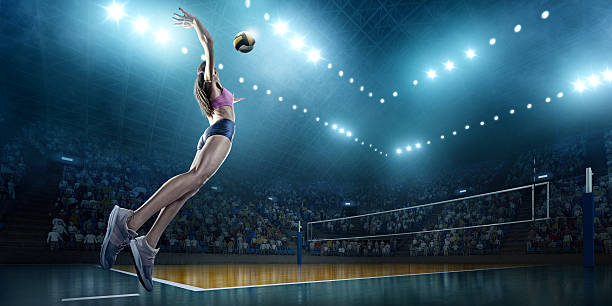 Volleyball: Female player in action Beautiful female volleyball player performs an emotional game moment on the indoor volleyball stadium with bleachers full of people. She is wearing an unbranded sports cloth. Volleying stock pictures, royalty-free photos & images