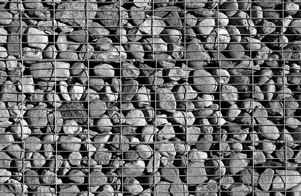 Pile of stones behind metal grid. Background and texture for design.
