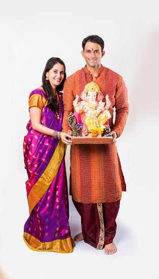 portrait of smart Indian couple holding Ganesh idol or ganpati idol, isolated over white background