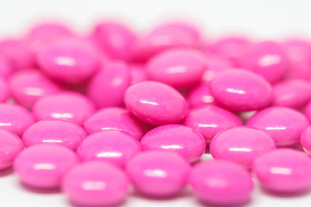 istock Pink medicine pills on wooden background , selective focus 592392336