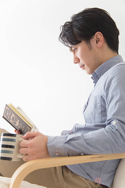 istock Japanese man sitting reading with a cup of coffee 592393084