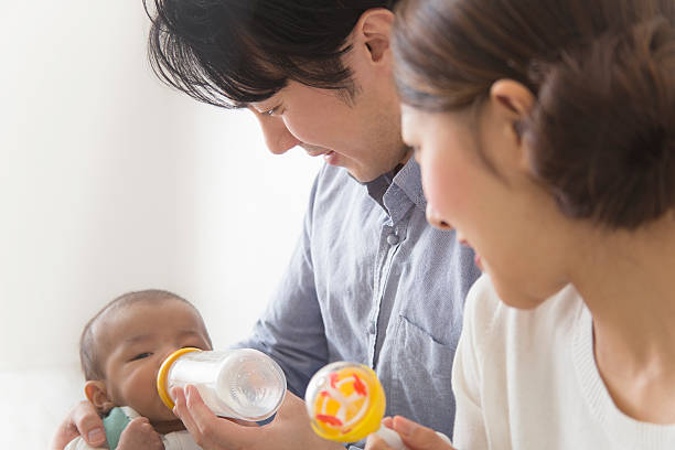 日本のカップルは、ボトルから赤ちゃんのミルクを供給 - 赤ちゃん　ミルク ストックフォトと画像