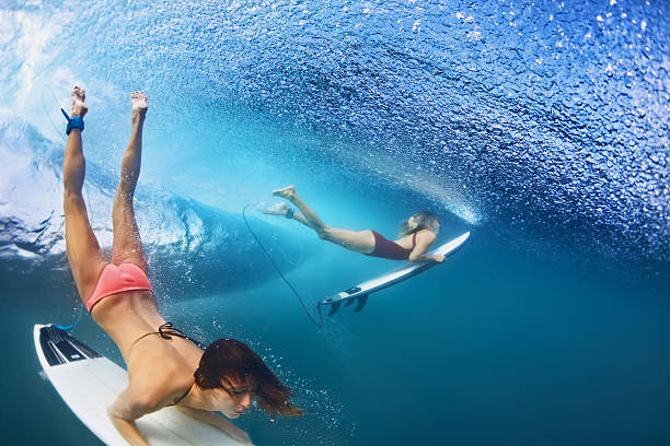 サーフボードで水の下でダイビング美しいサーファーの女の子 - wave breaking ストックフォトと画像