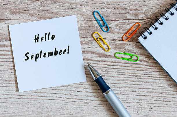 istock Hello September wrote at paper sticker on wooden workplace background 592397814