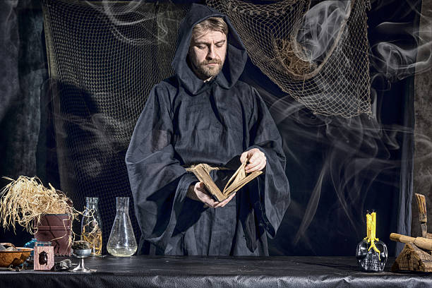 istock Halloween. The medieval alchemist reading a book 592400182