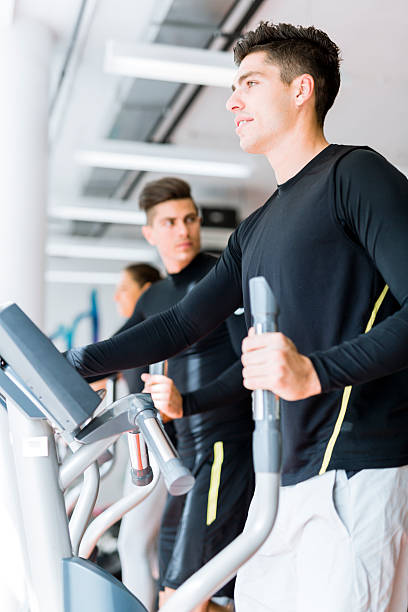 istock Young healthy group of people working out on elliptic trainer 592402454